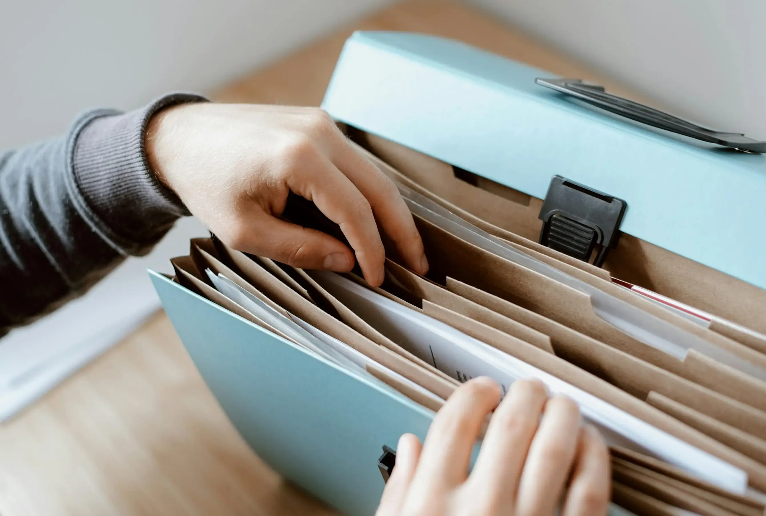 Una mano mirando papeles en una carpeta de archivos