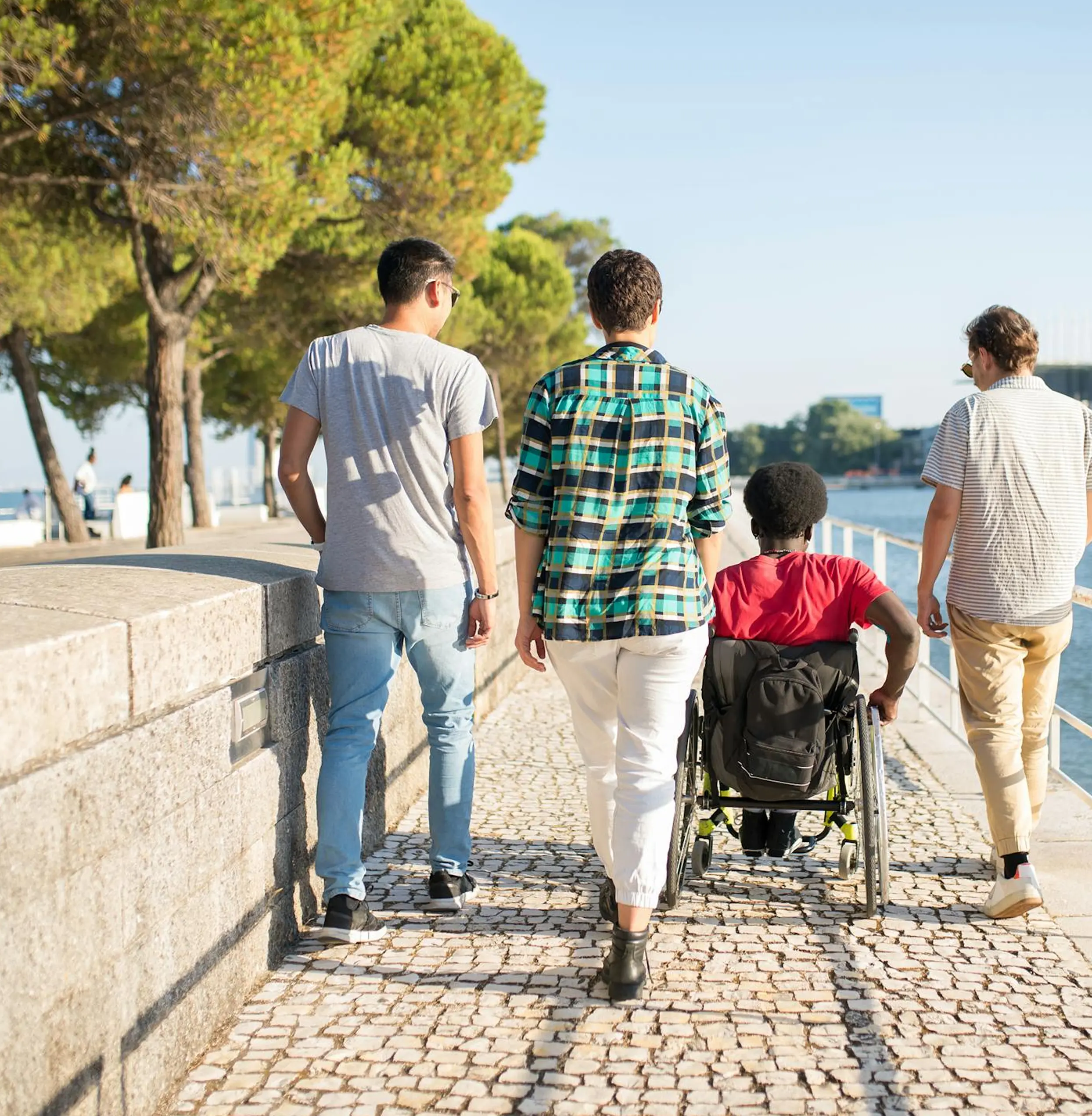 Persone che passeggiano e accompagnano una persona in sedia a rotelle